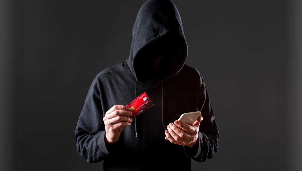 front-view-male-hacker-holding-smartphone-credit-card (1)